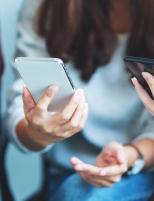 Grupa młodych ludzi przegląda swoje smartfony siedząc razem