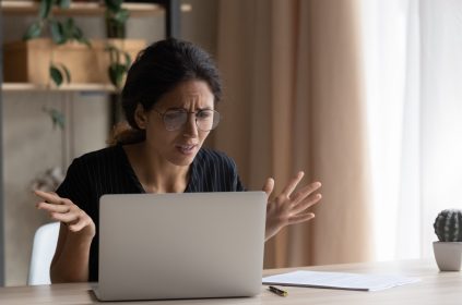 Zdenerwowana kopieta patrzy na ekran laptopa