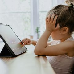 Dziewczynka siedzi przy stole z tabletem