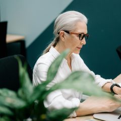 Starsza pani wpisuje tekst na klawiaturze laptopa
