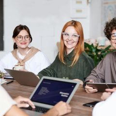 Młodzi ludzie siedzący z laptopami przy stole.