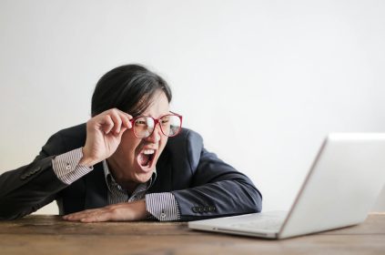 Mężczyzna z niedowierzaniem patrzy na ekran laptopa