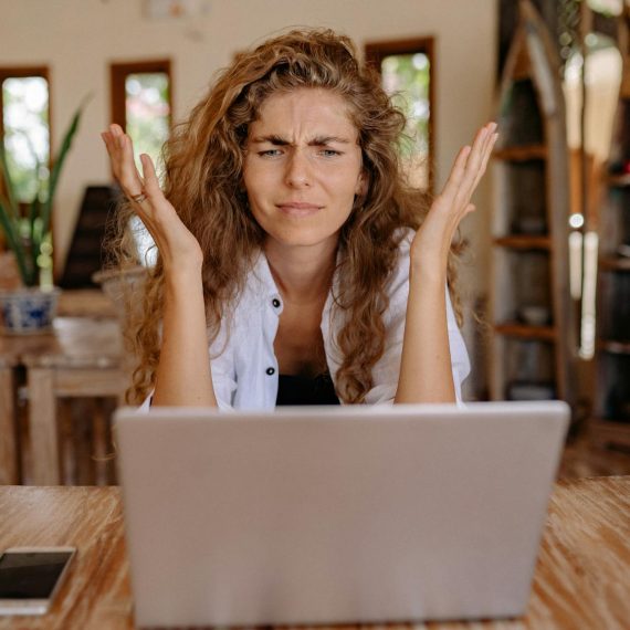 Zdenerwowana dziewczyna w geście bezradności spogląda na ekran laptopa
